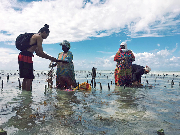 Kevin Williams standing in sea with local women in Tanzania