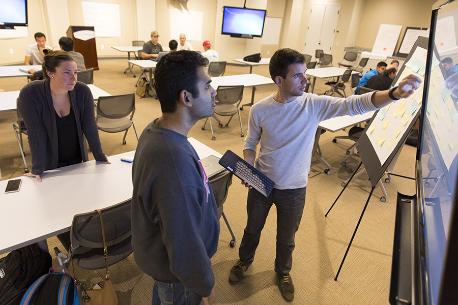 Second year MBA students Andrea Elliott, left to right, Rishi Chatterjee, and Chris Henseler use one of the Sharp Aquos Board interactive displays as they work on their project together in lecturer David Sutherland's Innovative Business Projects course in the Innovation Lab inside Correll Hall.